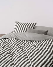 Bettwäsche-Set mit schwarz-weißen Streifen, bestehend aus einem Kissenbezug und einem Bettdeckenbezug, aus der Perspektive von vorne fotografiert.