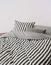 Bettwäsche-Set mit schwarz-weißen Streifen, bestehend aus einem Kissenbezug und einem Bettdeckenbezug, aus der Perspektive von vorne fotografiert.