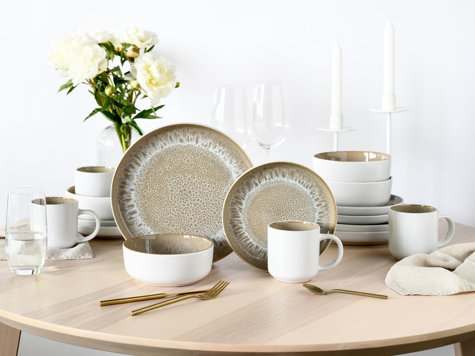 Kombiservice 16-tlg. Sand auf einem Tisch, bestehend aus Tellern, Schalen und Tassen in einem eleganten, sandfarbenen Design. Perspektive von vorne.