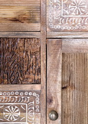 Nahaufnahme eines Holzmöbels mit verschiedenen Texturen und geschnitzten Mustern, seitliche Perspektive.