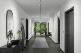 Moderner Flur mit Schienenspot Tubo an der Decke, Blick in Richtung Garten durch Glastüren.