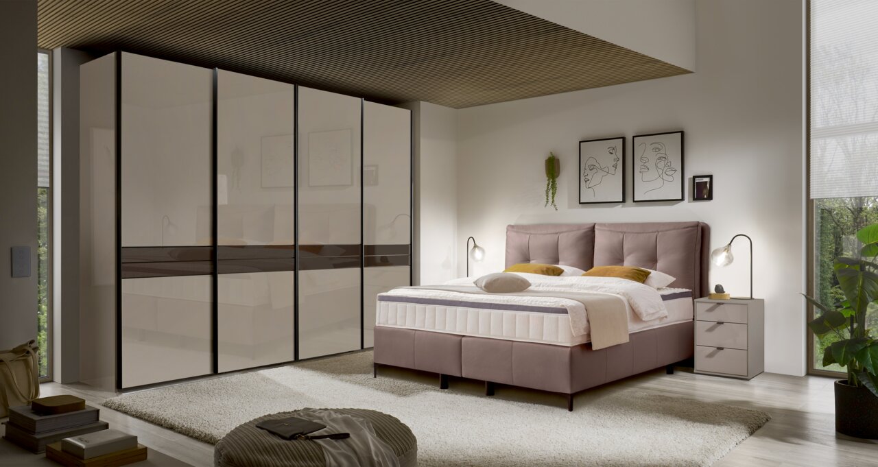 Modernes Boxspringbett in einem stilvollen Schlafzimmer, seitliche Perspektive mit Nachttisch und dekorativen Elementen.