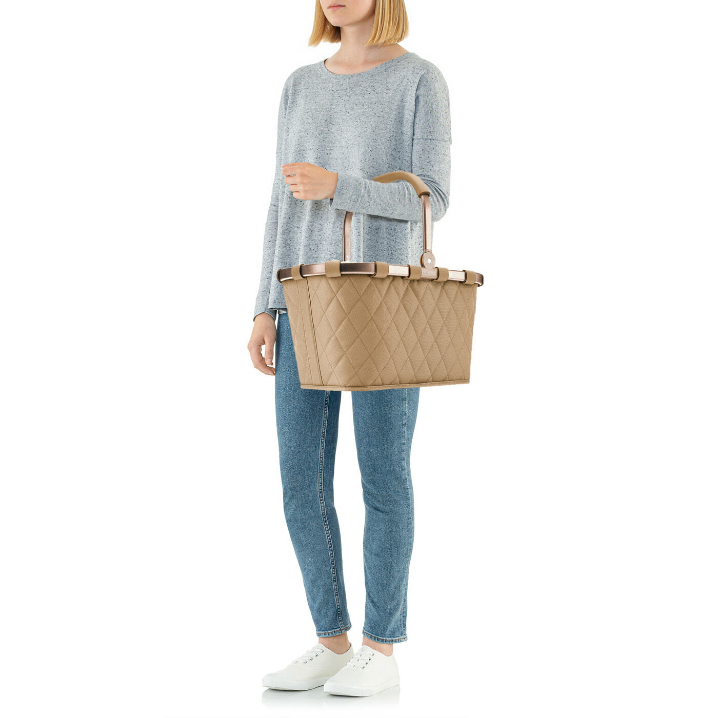 Frau in lässiger Kleidung hält eine beige, rautenförmig gesteppte Tragetasche mit Griffen, seitliche Perspektive
