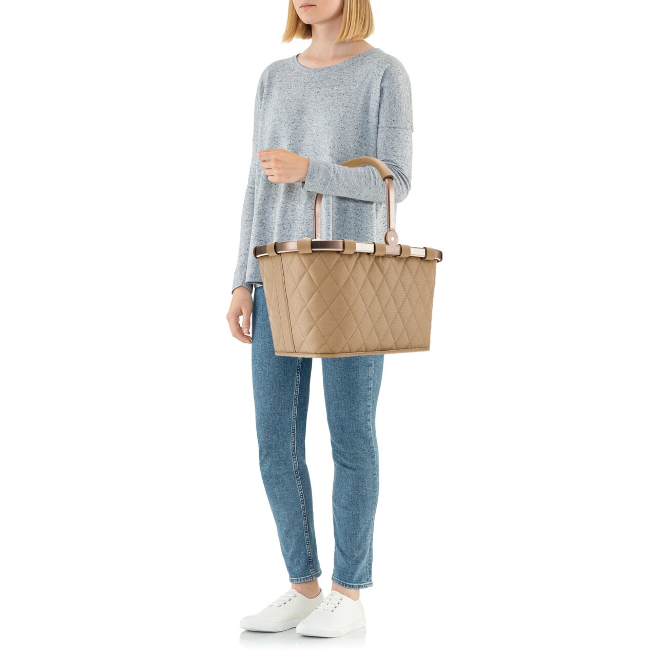 Frau in lässiger Kleidung hält eine beige, rautenförmig gesteppte Tragetasche mit Griffen, seitliche Perspektive