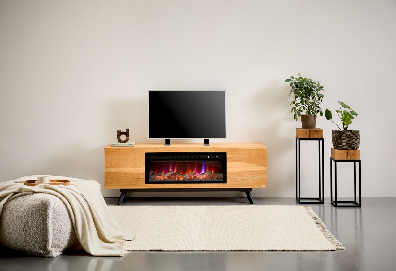 Modern tv-lowboard van licht hout met ingebouwde elektrische haard en vlammeneffect, met de tv erop, gefotografeerd vanaf ooghoogte in een woonkameromgeving.