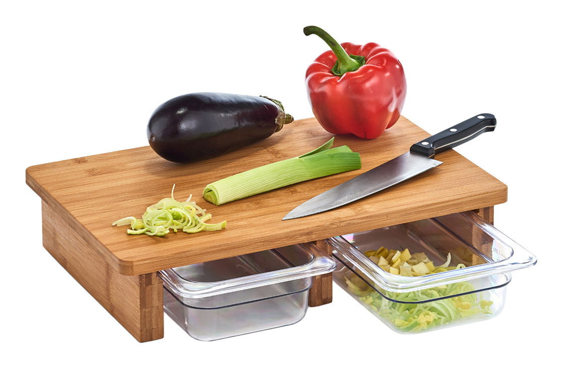 Schneidebrett aus Holz mit zwei Auffangschalen, darauf liegen ein Messer, eine Aubergine, eine rote Paprika und ein Lauch. Perspektive von schräg oben.