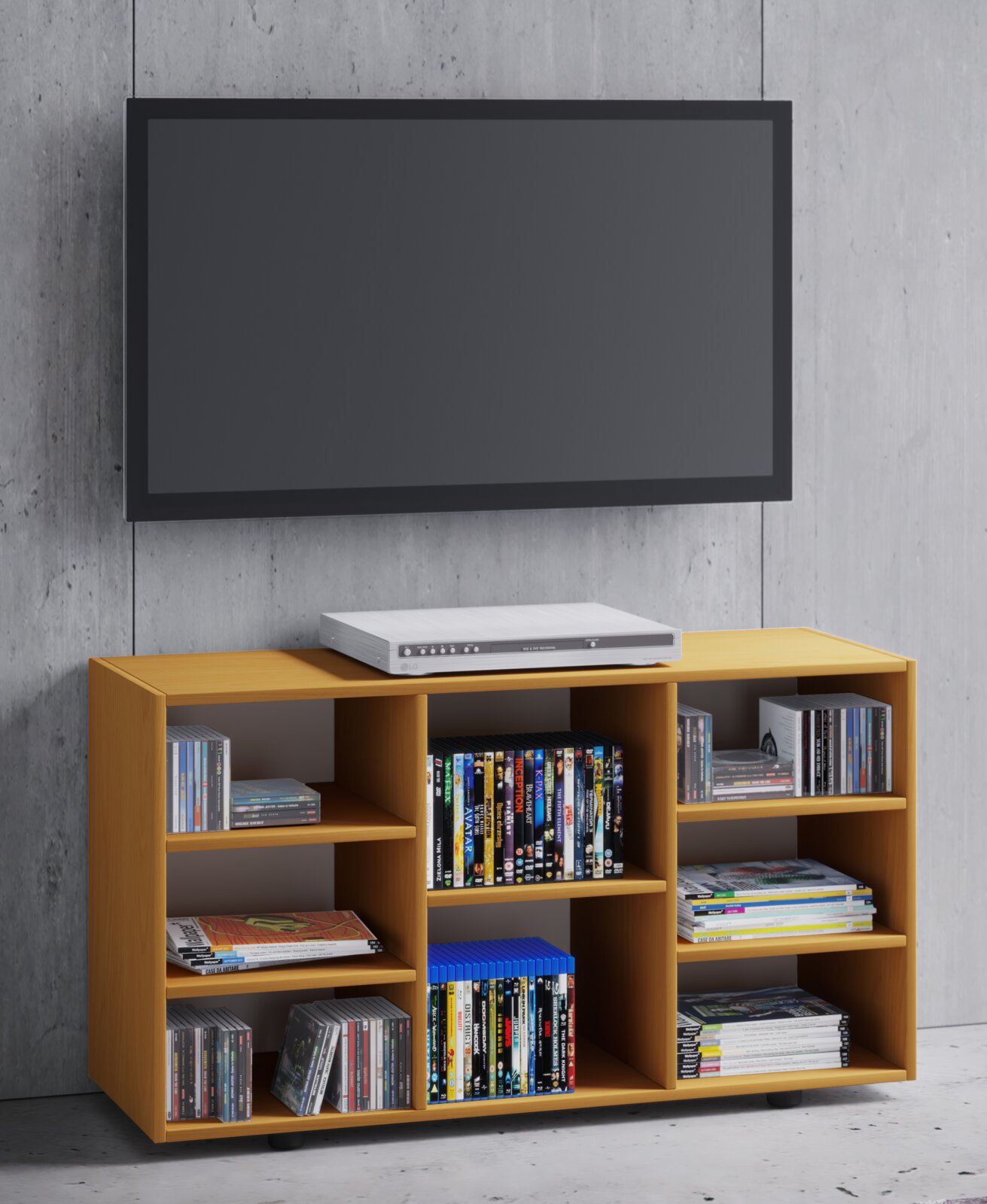 Modernes TV-Lowboard/Medienregal aus hellem Holz mit offenen Fächern für DVDs, CDs und Zeitschriften, vorne in leichter Schrägansicht vor Betonwand, darüber ein wandmontierter Flachbildfernseher und ein DVD-Player auf dem Möbel.