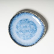 Runder Keramikteller in Blau mit verlaufender, gesprenkelter Glasur und dunklem Rand, fotografiert in Draufsicht von oben auf weißem Hintergrund