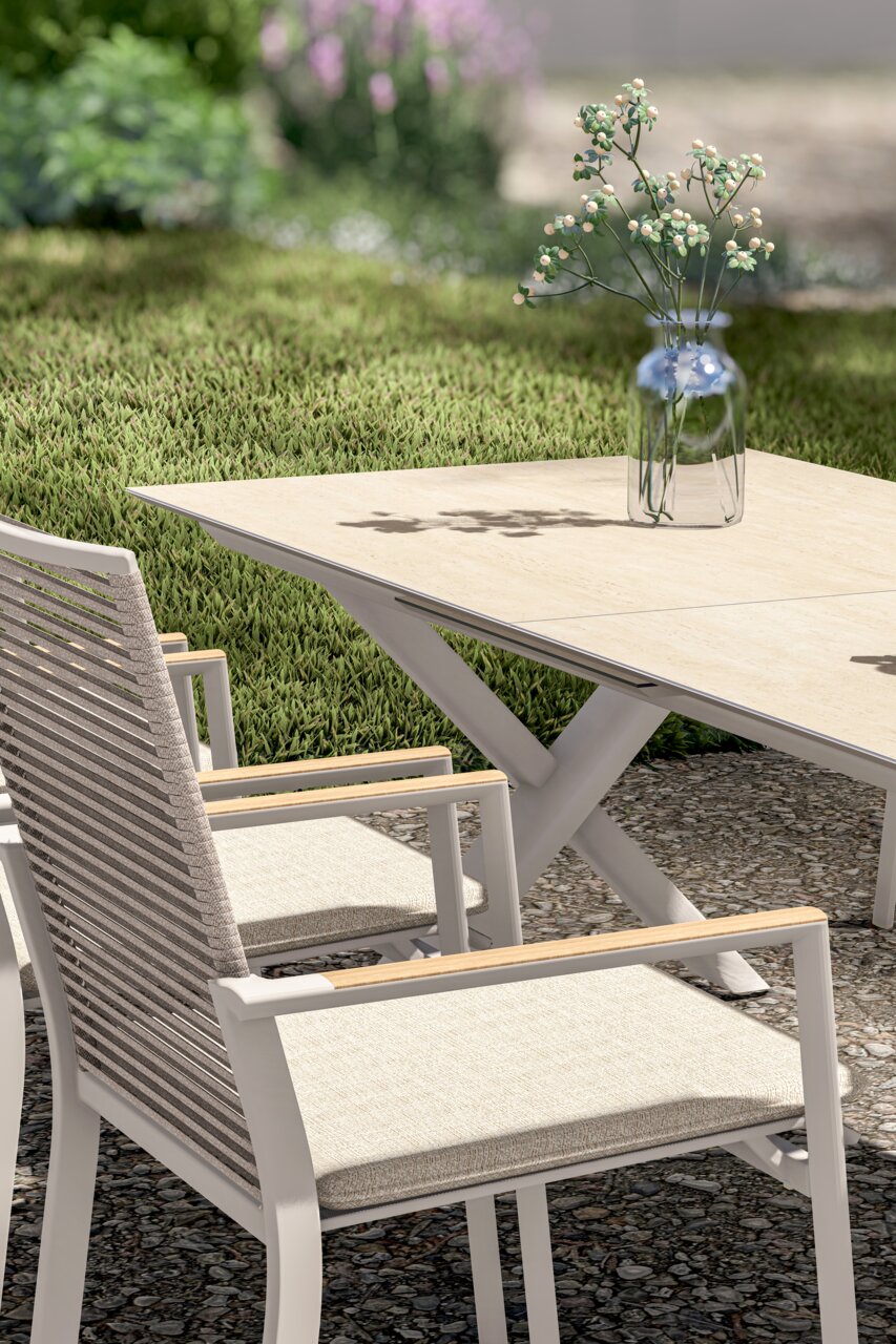 Moderne tuinstoel en uitschuifbare tafel van licht hout en metaal, zijaanzicht met uitzicht op een groene tuin.