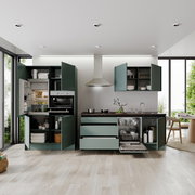 Moderne Küchenzeile mit grünen Schränken, eingebautem Ofen, Kühlschrank und Geschirrspüler, aus der Perspektive eines hellen, offenen Raumes mit Blick auf den Garten.