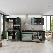 Moderne Küchenzeile mit grünen Schränken, eingebautem Ofen, Kühlschrank und Geschirrspüler, aus der Perspektive eines hellen, offenen Raumes mit Blick auf den Garten.