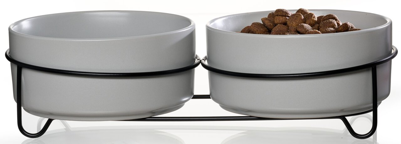 Zweierset grauer Futternäpfe auf schwarzem Metallgestell, einer gefüllt mit Trockenfutter, seitliche Perspektive.