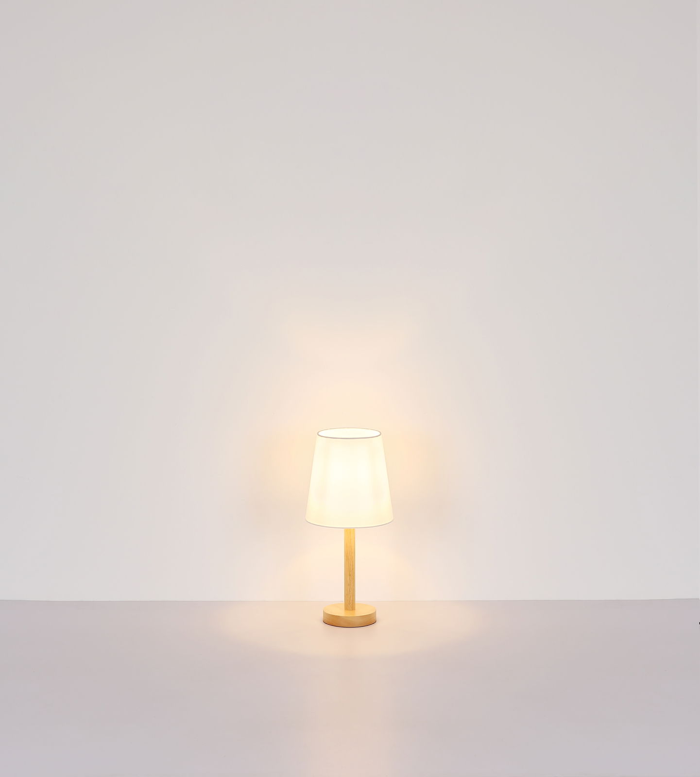 Tischleuchte mit Holzfuß und weißem Lampenschirm, frontal fotografiert vor einer neutralen Wand.