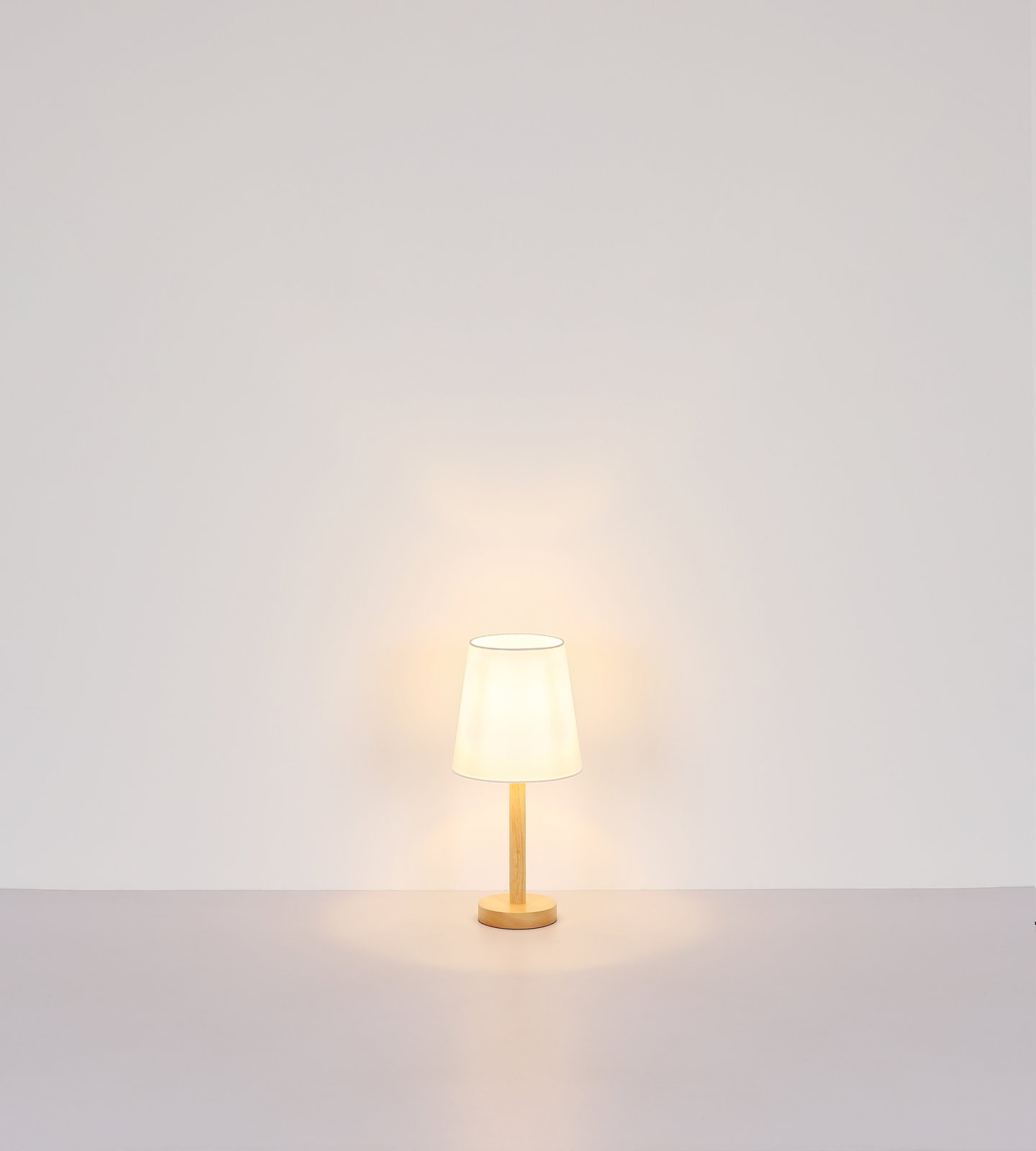 Tischleuchte mit Holzfuß und weißem Lampenschirm, frontal fotografiert vor einer neutralen Wand.