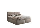Boxspringbett in seitlicher Perspektive mit grauem Stoffbezug, dekoriert mit Kissen und Decken.