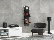 Schwarzes, wandmontiertes Vinyl-Schallplattenregal mit mehreren Fächern, bestückt mit Schallplatten und Covern, in moderner Wohnzimmerszene; frontale Ansicht mit leichtem Blick von links.