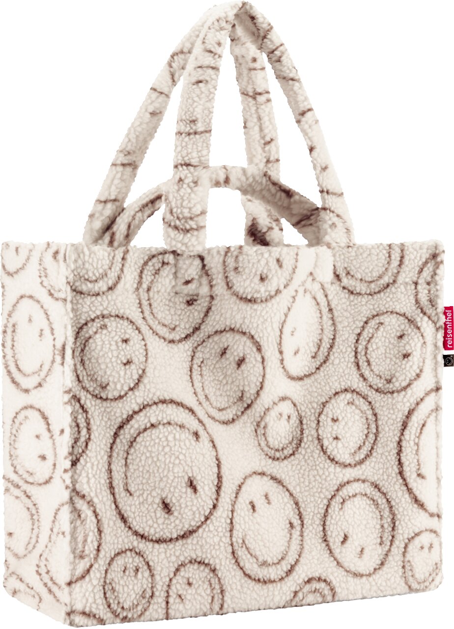 Kuschelige Teddyfell-Shopper-Tasche in Cremeweiß mit braunem Smiley-Muster und zwei Tragehenkeln, Produktansicht schräg von vorne auf weißem Hintergrund
