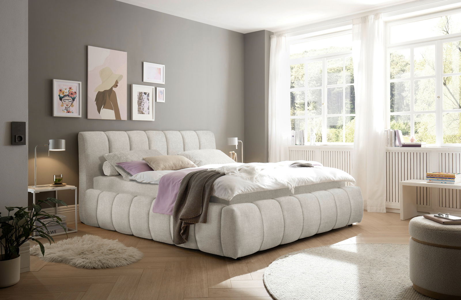 Modernes Polsterbett in einem hellen Schlafzimmer mit großen Fenstern, seitliche Perspektive.