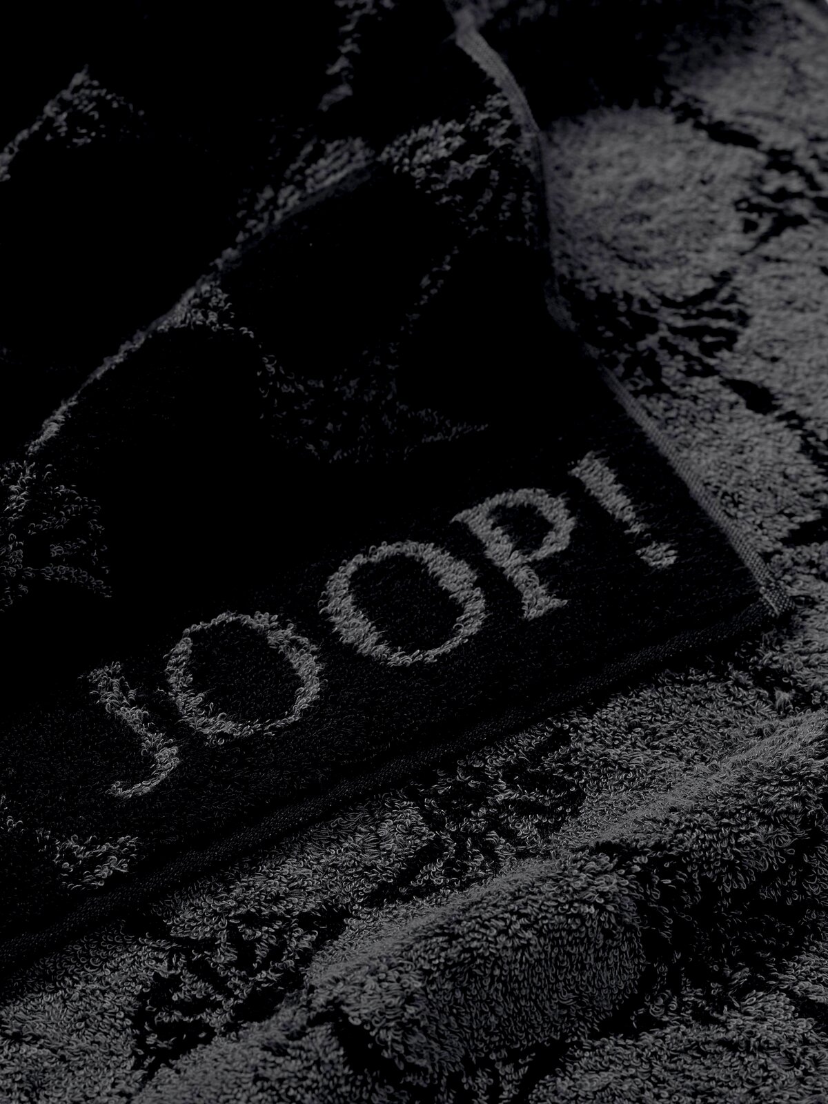 JOOP! Handtuch CORNFLOWER CLASSIC Nahaufnahme eines luxuriösen, dunkelgrauen Handtuchs mit eingewebtem Muster und dem Schriftzug 'JOOP!'