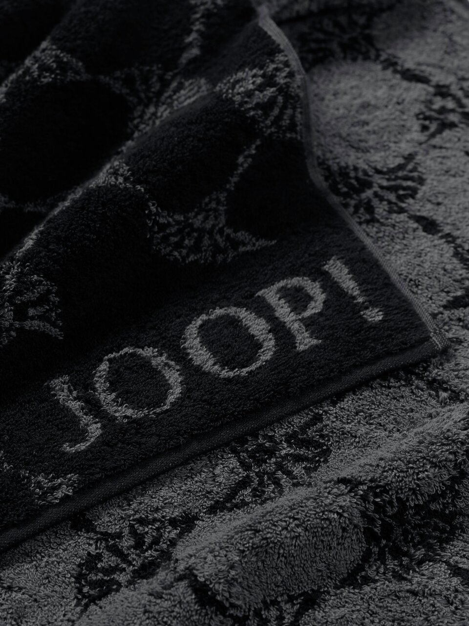 JOOP! Handtuch CORNFLOWER CLASSIC Nahaufnahme eines luxuriösen, dunkelgrauen Handtuchs mit eingewebtem Muster und dem Schriftzug 'JOOP!'