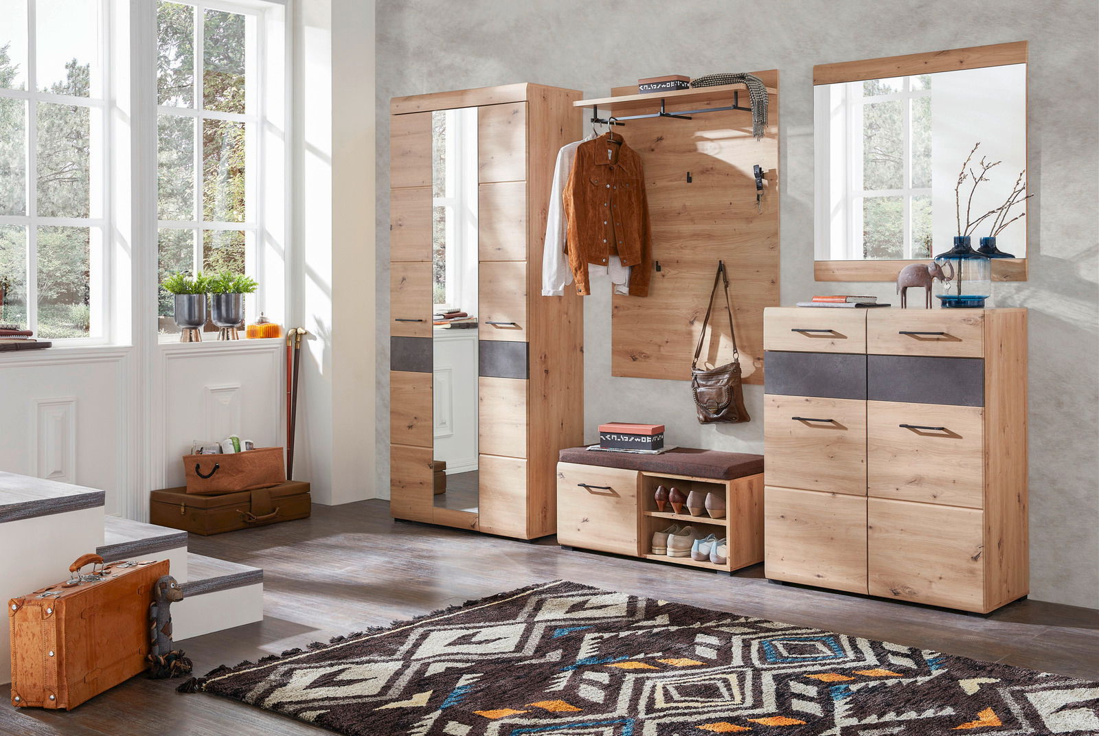 Garderoben-Set aus Holz mit Spiegel, Kleiderhaken und Schuhablage in einem hellen Raum mit großen Fenstern, aus der Perspektive von vorne betrachtet.