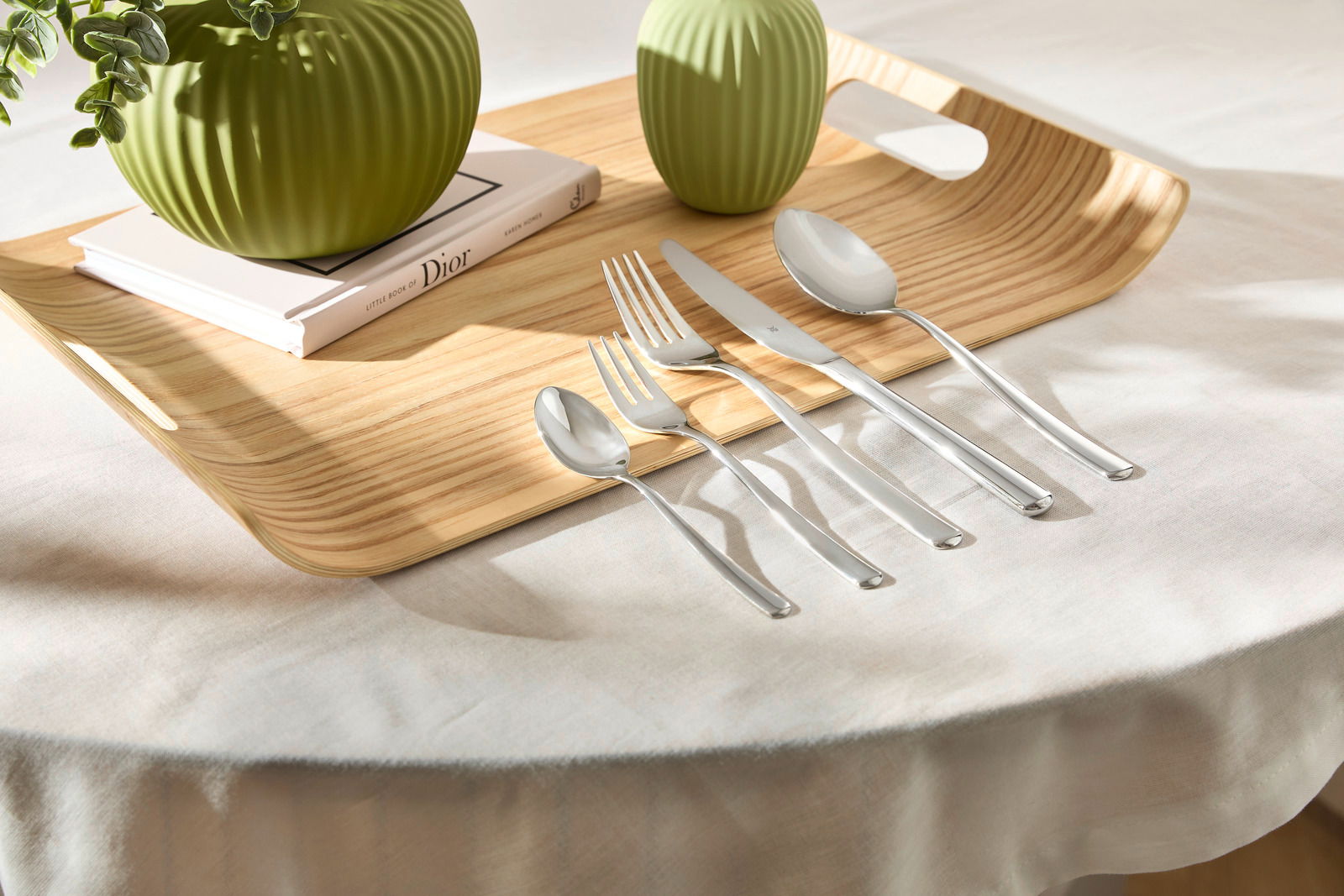 WMF Besteckset 60-tlg BOSTON Besteckset Boston 60-tlg. auf einem Holztablett mit grünen Vasen, von oben fotografiert.