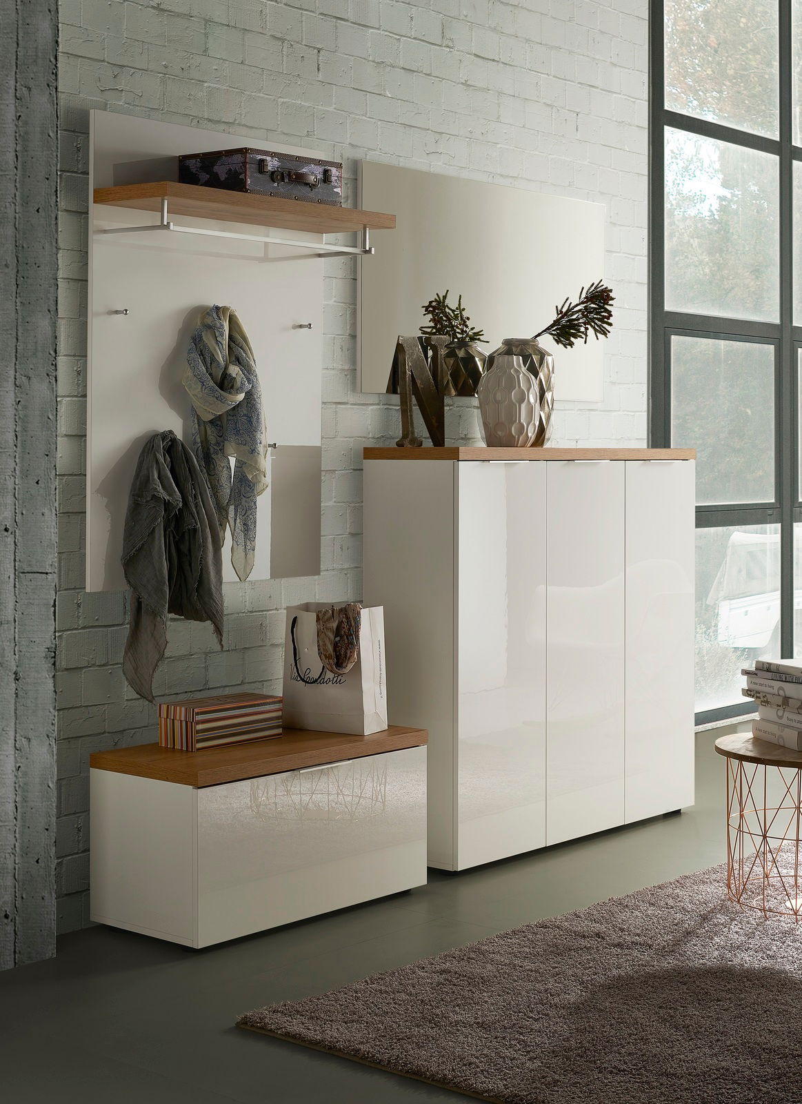 Moderne Garderobeneinrichtung mit weißem Hochglanz-Schuhschrank, passendem Garderobenpaneel und Spiegel, seitliche Perspektive