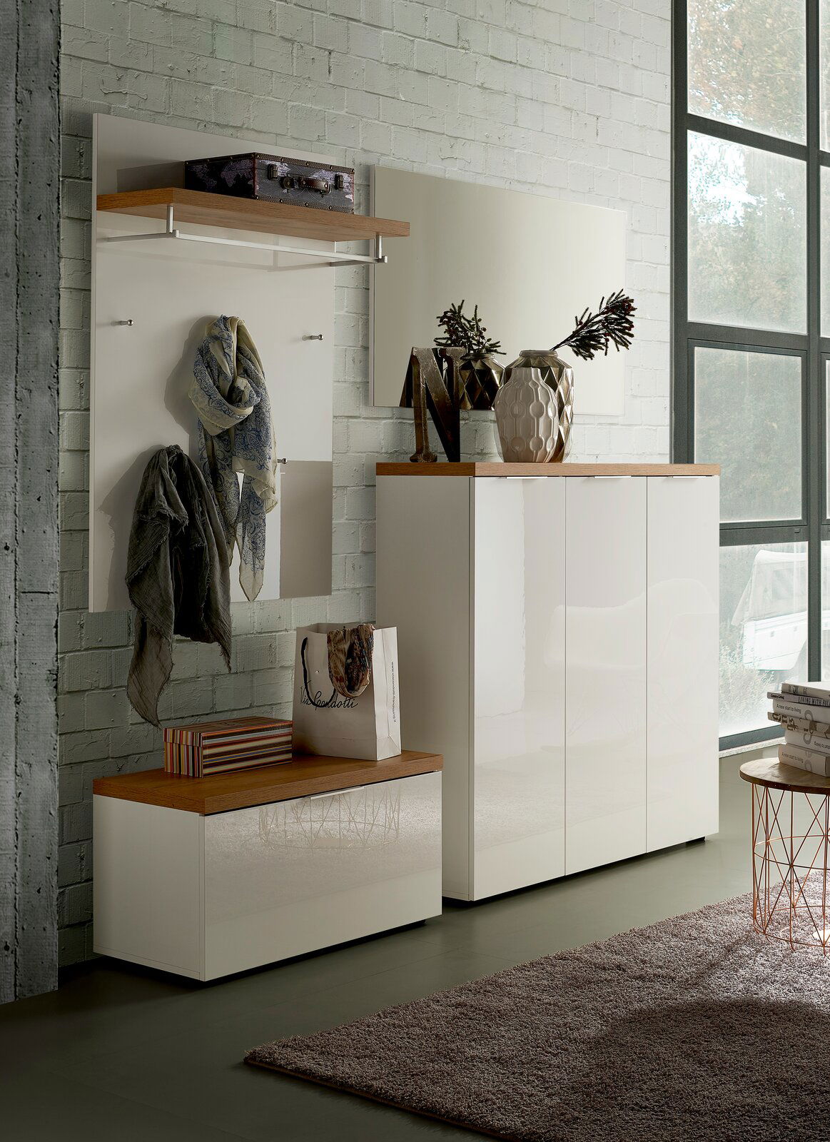 Moderne Garderobeneinrichtung mit weißem Hochglanz-Schuhschrank, passendem Garderobenpaneel und Spiegel, seitliche Perspektive