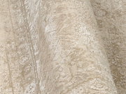 Nahaufnahme eines Designer-Teppichs mit beige-weißen Mustern in schräger Perspektive.