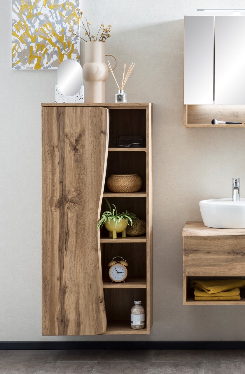 Midischrank 60 aus Holz mit natürlicher Maserung, linke Perspektive, mit dekorativen Elementen wie Pflanze, Uhr und Körben.