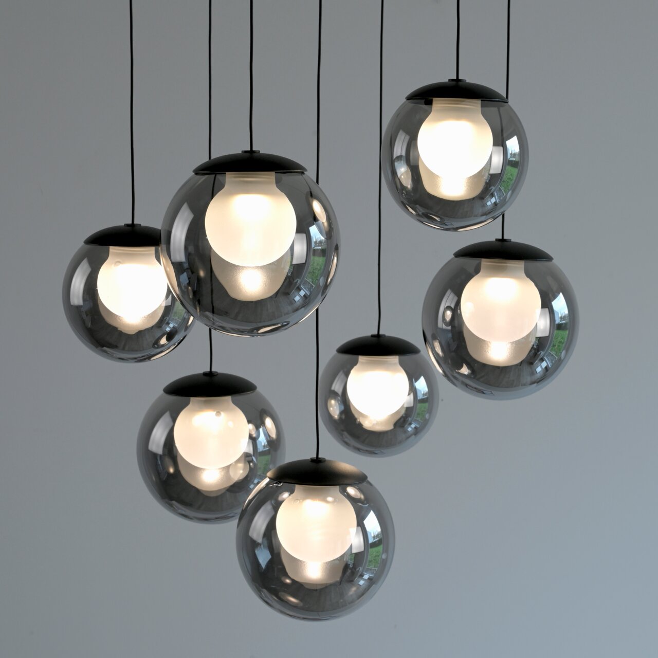 Moderne LED-Pendelleuchte mit sieben kugelförmigen, transparenten Lampenschirmen, von unten betrachtet.