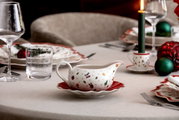 Weihnachtlich dekorierte Sauciere mit Unterteil auf einem festlich gedeckten Tisch, seitliche Perspektive