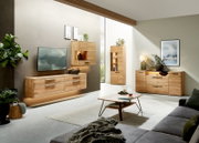 Modernes Wohnzimmer mit hellen Massivholz-Möbeln: schwebendes TV-Lowboard, Hängeelement mit Beleuchtung, Vitrine und Sideboard mit Griffen; Frontansicht aus leicht schräger Perspektive.