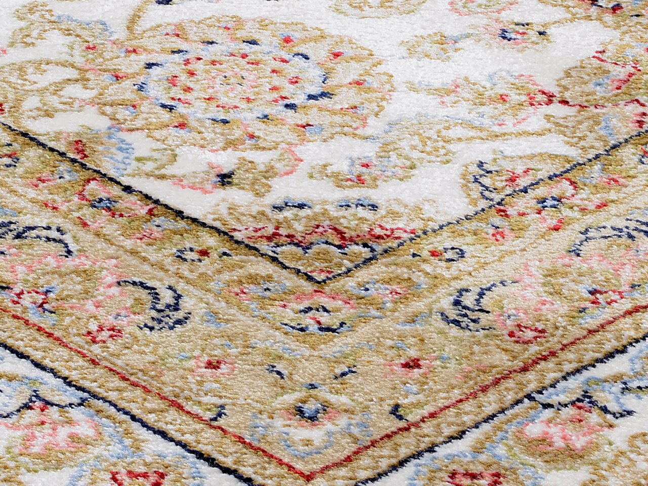 Nahaufnahme eines Orientteppichs mit floralen Mustern in Beige, Rot und Blau, schräg von oben fotografiert.