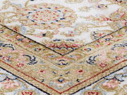 Nahaufnahme eines Orientteppichs mit floralen Mustern in Beige, Rot und Blau, schräg von oben fotografiert.