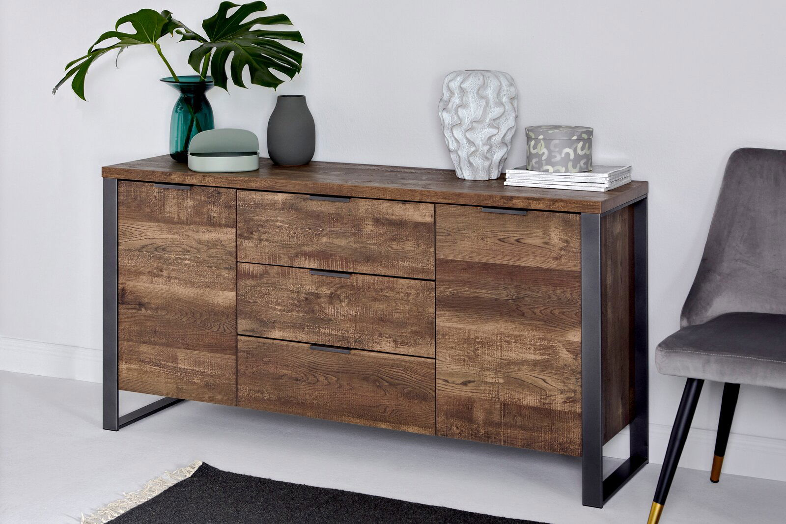 Jahnke Sideboard LOOP Holz-Sideboard mit drei Schubladen und zwei Türen, dekoriert mit Vasen und Pflanzen, aus seitlicher Perspektive fotografiert.