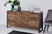 Holz-Sideboard mit drei Schubladen und zwei Türen, dekoriert mit Vasen und Pflanzen, aus seitlicher Perspektive fotografiert.
