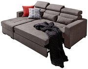 Großes, modernes Ecksofa in Grau mit verstellbaren Kopfstützen, dekoriert mit roten und gemusterten Kissen sowie einer dunklen Strickdecke, Perspektive von vorne links.