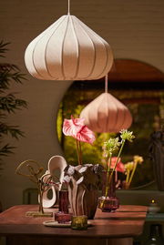 Vase mit floralen Verzierungen auf einem Tisch, umgeben von dekorativen Elementen, aus der Frontalperspektive betrachtet.