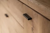 Nahaufnahme eines Holzschranks mit schwarzem Griff, Perspektive von schräg oben.