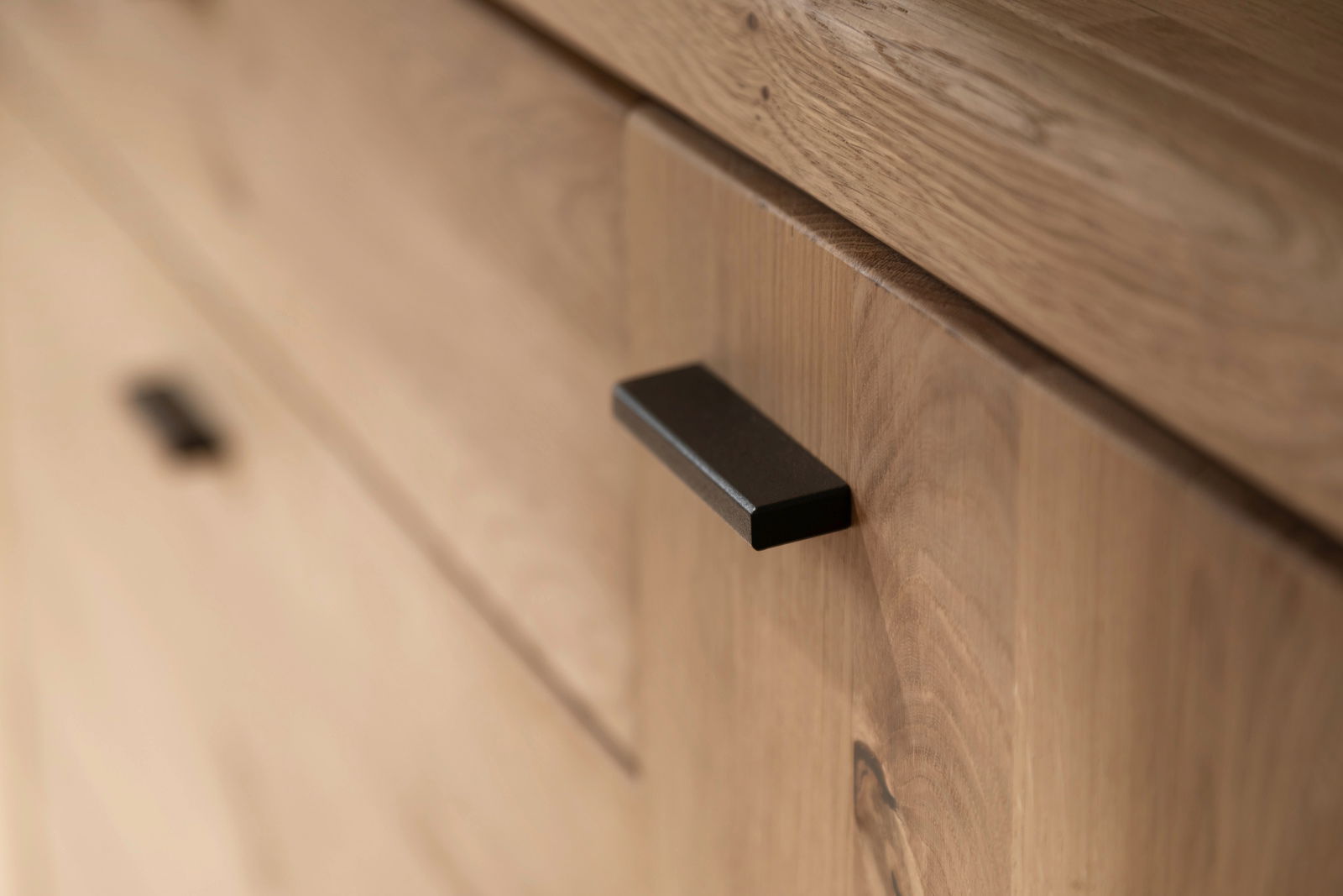 Nahaufnahme eines Holzschranks mit schwarzem Griff, Perspektive von schräg oben.