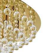 Nahaufnahme einer luxuriösen Deckenleuchte mit goldenen Elementen und funkelnden Kristallanhängern, von unten betrachtet.