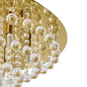 Close-up van een luxe plafondlamp met gouden elementen en schitterende kristallen hangers, gezien van onderaf.