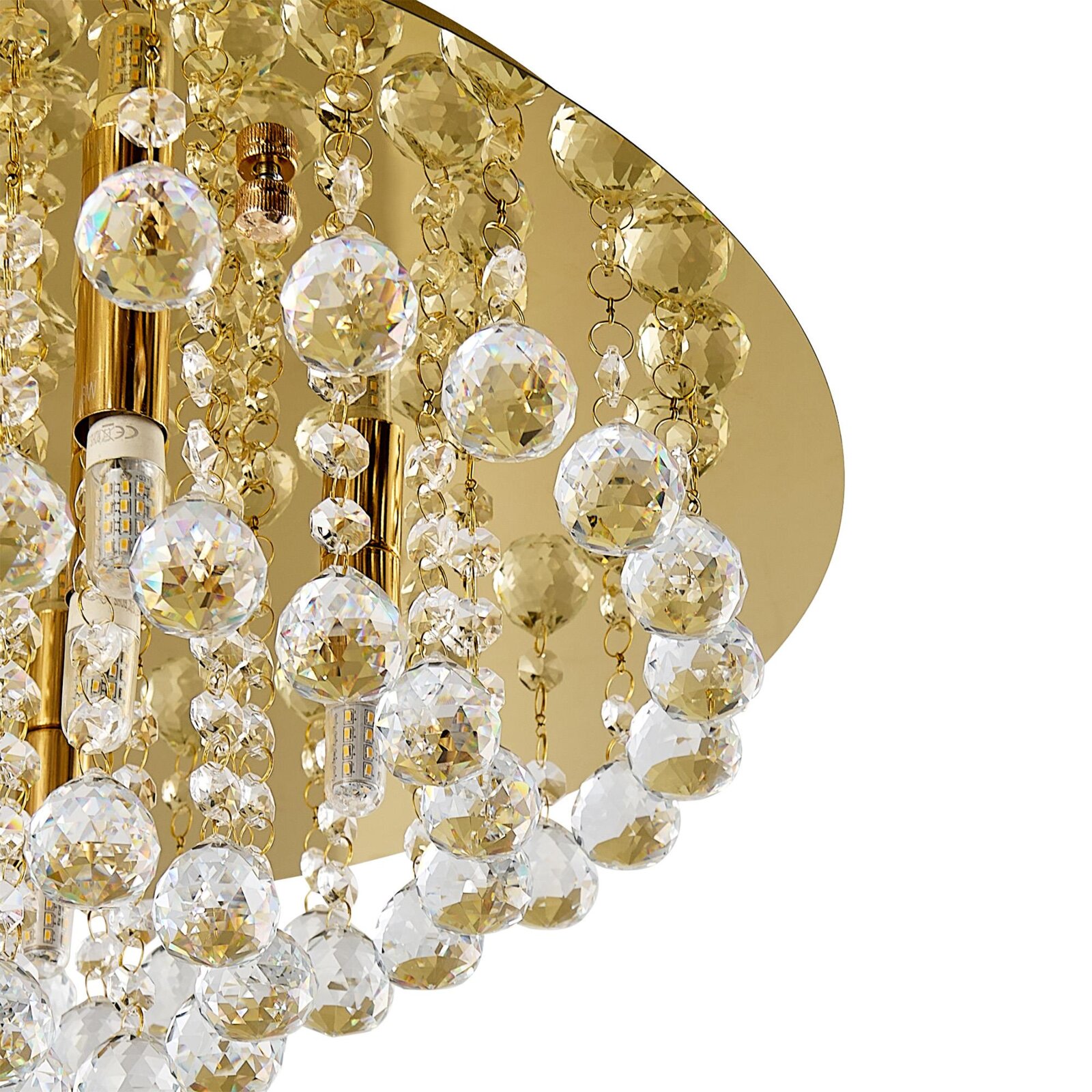 Close-up van een luxe plafondlamp met gouden elementen en schitterende kristallen hangers, gezien van onderaf.