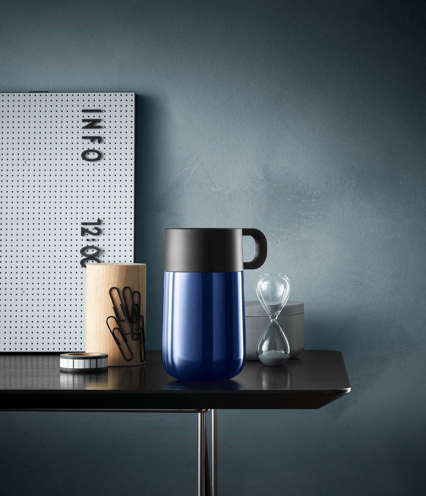 Impulse Travel Mug 0,3l Cromar in Blau mit schwarzem Deckel, seitliche Perspektive auf einem Tisch mit Büroaccessoires.