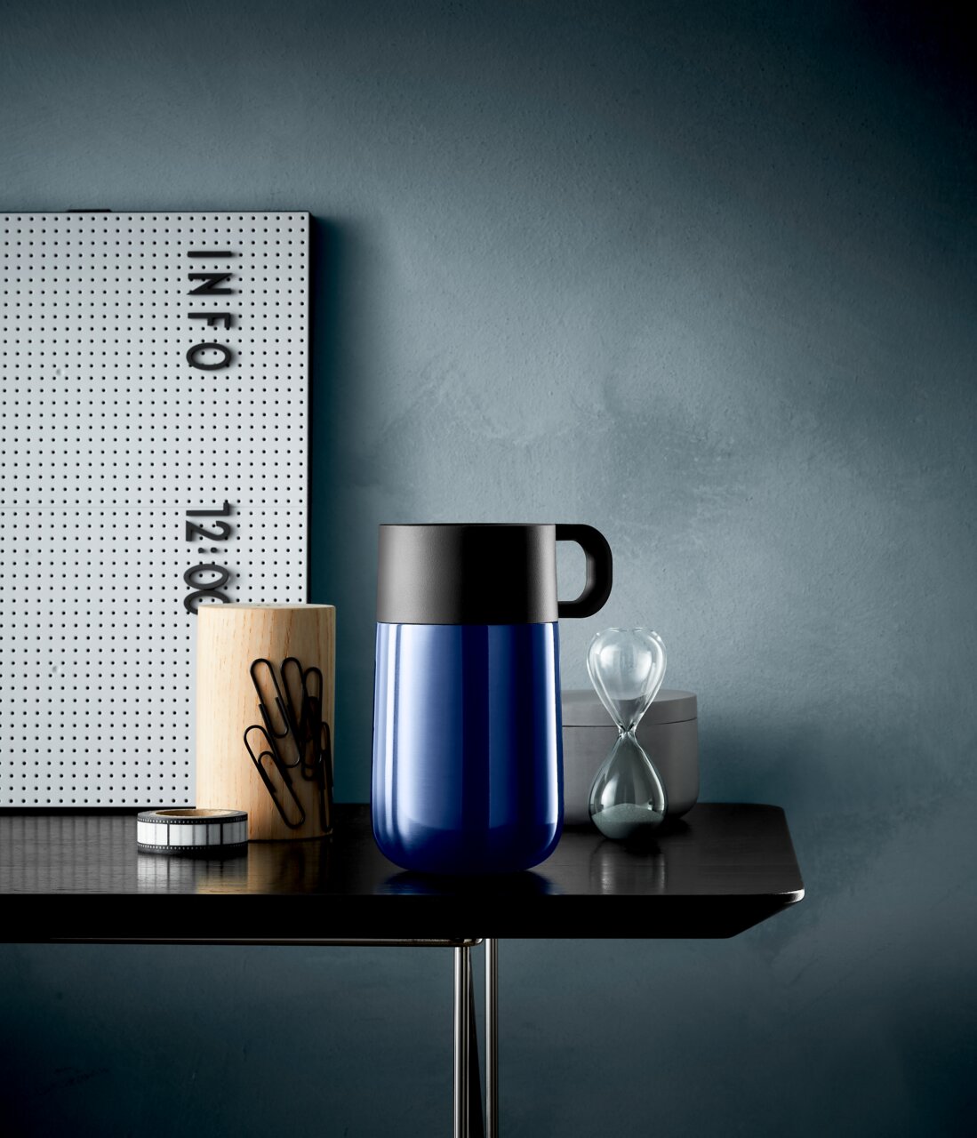 Impulse Travel Mug 0,3l Cromar in Blau mit schwarzem Deckel, seitliche Perspektive auf einem Tisch mit Büroaccessoires.