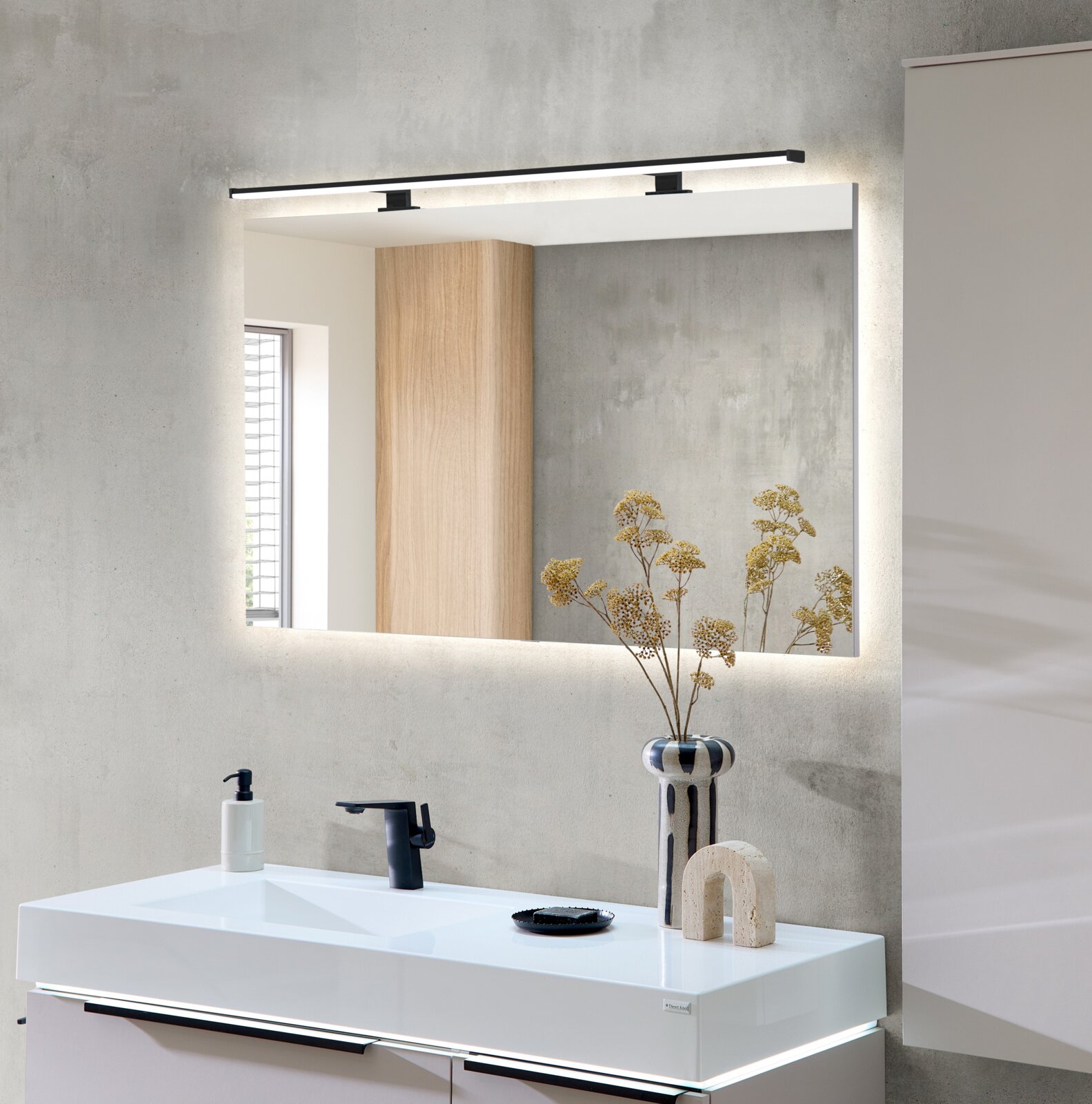 Dieter Knoll Wastafelset MEZZANO Moderne badkamer met een rechthoekige wandspiegel en een slanke zwarte led-wandlamp boven een witte wastafel, gezien van voren.