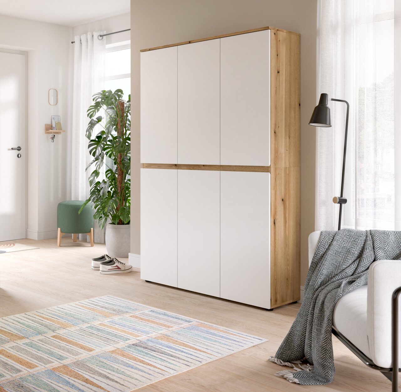 Hoher, moderner Schrank mit weißer Front und Holzrahmen im hellen Wohnraum, gezeigt in leichter Seitenansicht von vorn.