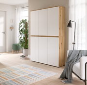 Hoher, moderner Schrank mit weißer Front und Holzrahmen im hellen Wohnraum, gezeigt in leichter Seitenansicht von vorn.