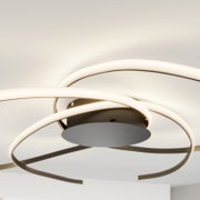 Moderne LED-Deckenleuchte mit drei überlappenden, ringförmigen Lichtbändern in Weiß und Metall, Ansicht von unten in leichter Untersicht